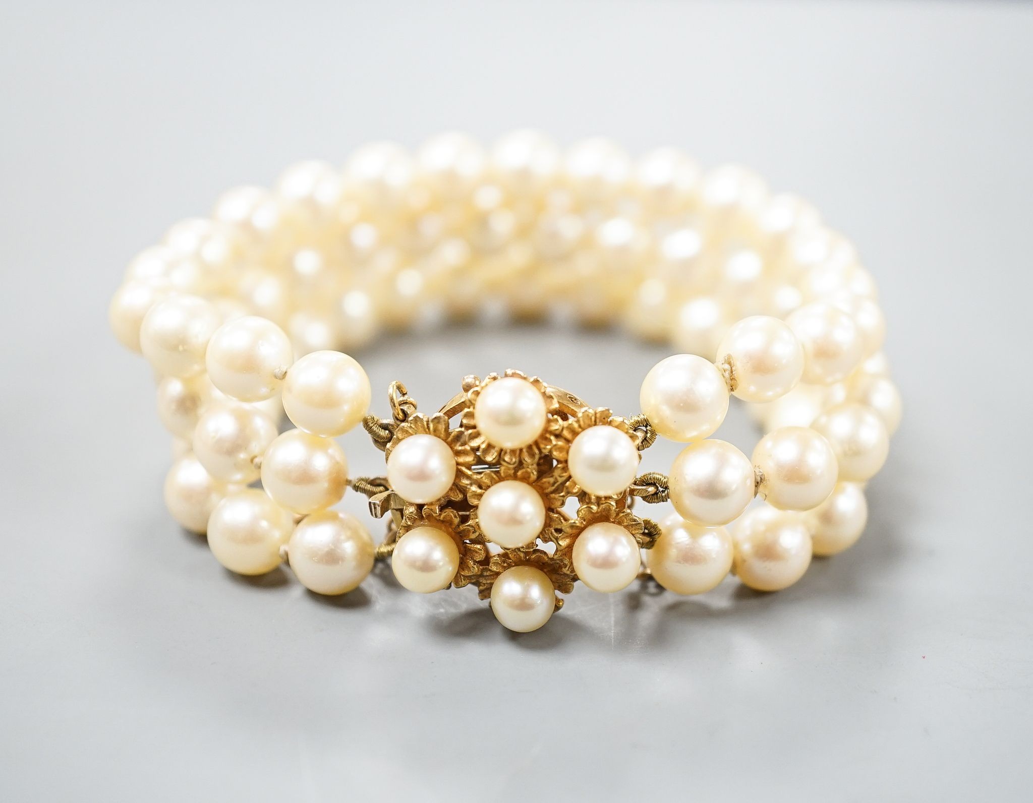 A triple strand cultured pearl bracelet, with yellow metal and cultured pearl cluster set clasp, approx. 16cm.